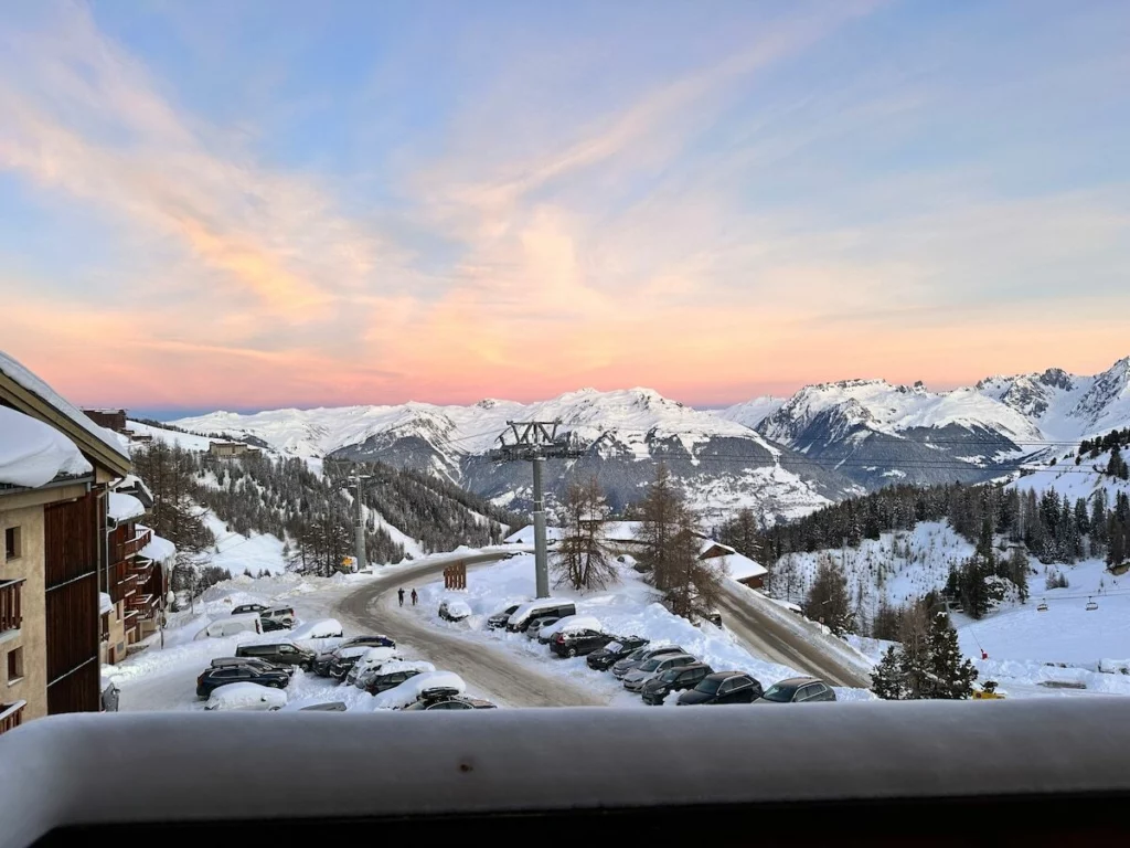 Coucher de soleil rose sur les sommets enneigés de La Plagne, vu depuis le balcon de l'appartement
