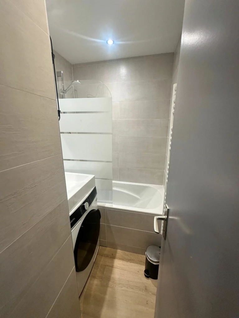 Salle de bain rénovée avec baignoire et lave-linge
