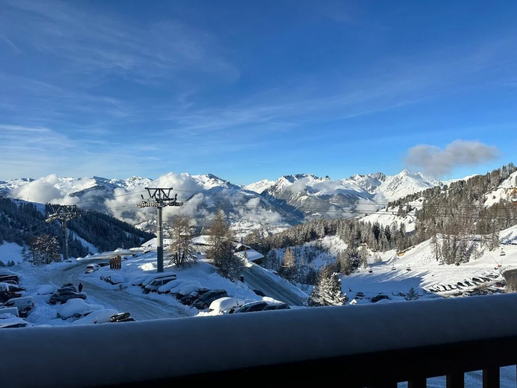 Montagnes enneigées et télésiège sous un ciel bleu, vus depuis le balcon